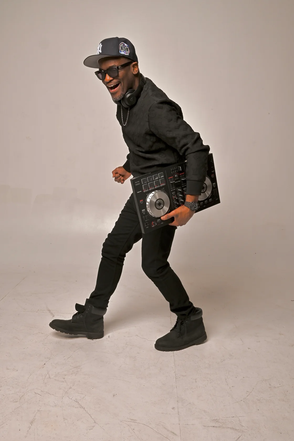 Mr. Sweety G smiling and carrying a DJ controller